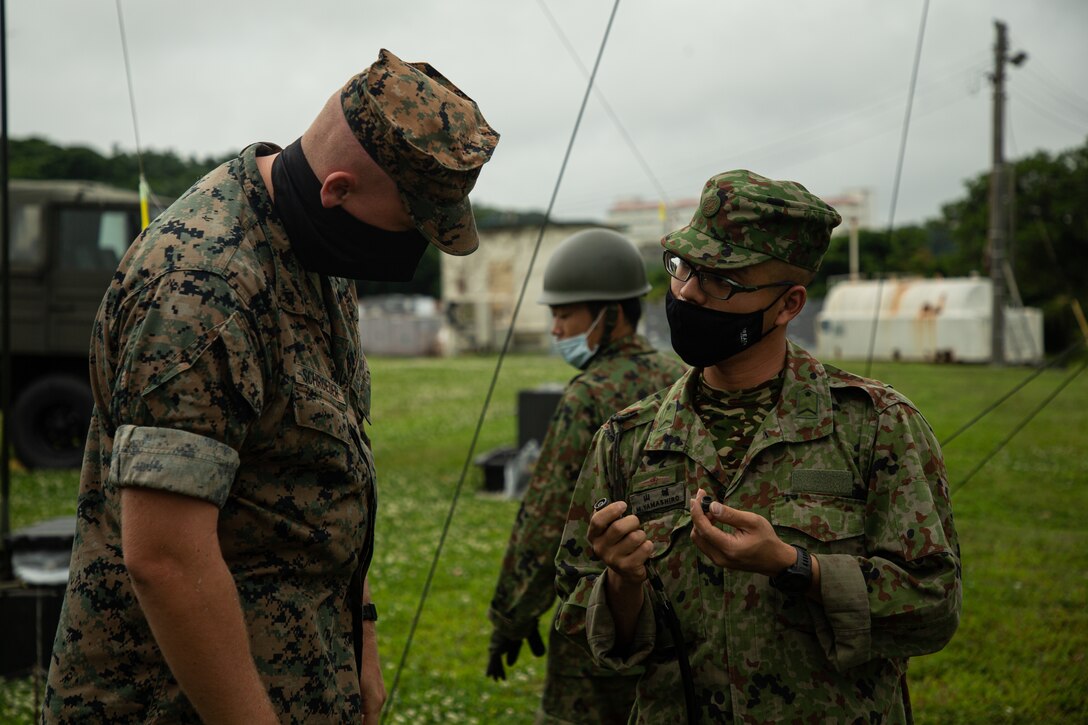 U.S. Marine Corps Lance Cpl. Hunter Schroeder, a network administrator with Marine Wing Communications Squadron (MWCS) 18, listens as a member of the Japanese 15th Signal Brigade inquires about a piece of radio equipment during a joint radio communications training exercise on Camp Foster, Okinawa, Japan, March 31, 2021.  MWCS-18 held a bi-lateral communications exercise in order to improve capabilities and diplomatic relations with the Japan Ground Self Defense Force.  (U.S. Marine Corps photo by Lance Cpl. Justin J. Marty)