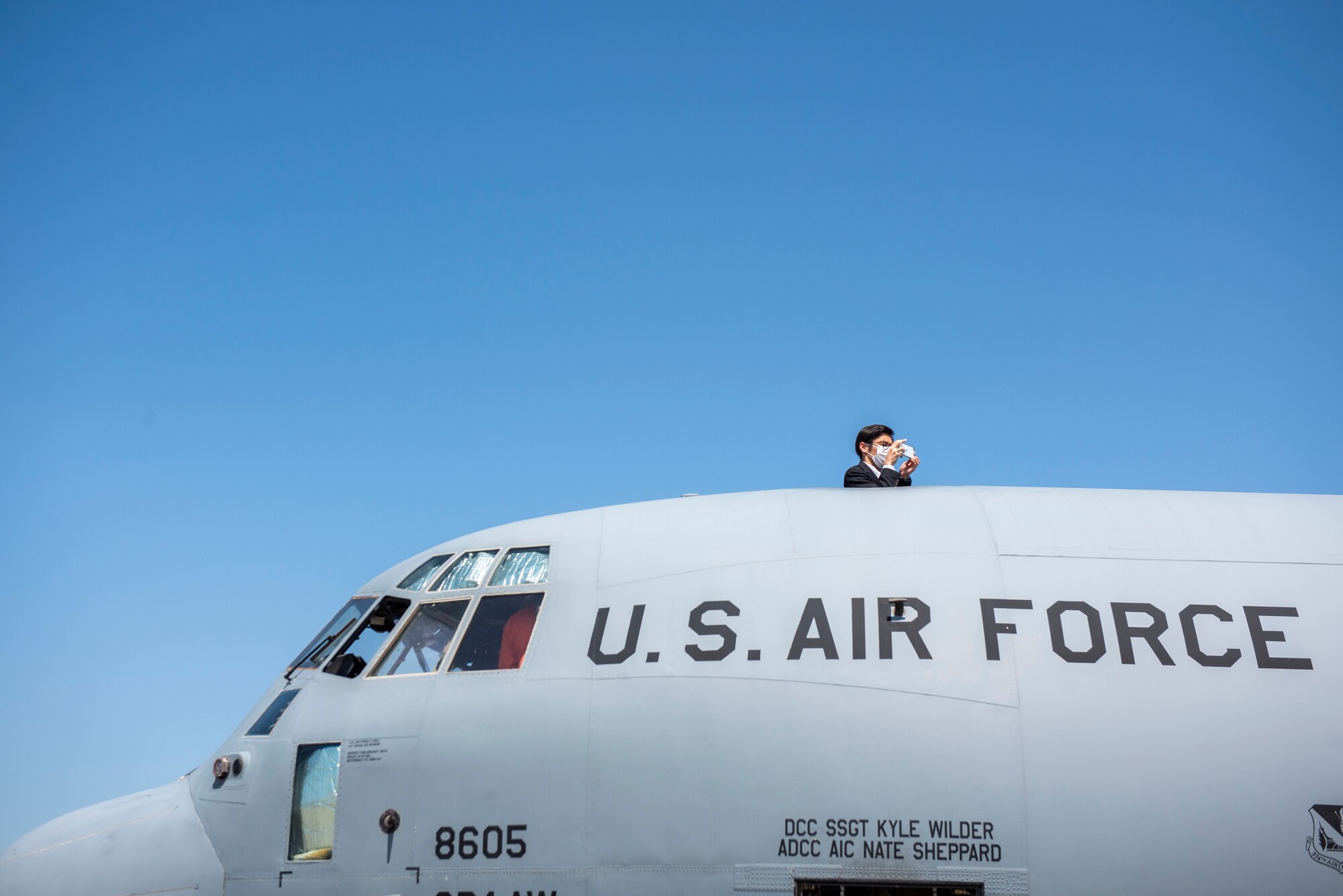Japanese Coast Guardsmen takes a photo of a C-130J Super Hercules