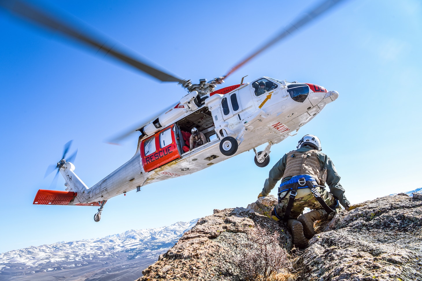 An MH-60S Knighthawk helicopter assigned to the "Longhorns" of Helicopter Search and Rescue (SAR) Squadron, practices pinnacle landings and extractions during a mountain flying SAR training event.