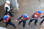 Sailors aboard the Arleigh Burke-class guided-missile destroyer USS Roosevelt (DDG 80) handle line during a replenishment-at-sea with the fast combat support ship USNS Supply (T-AOE 6), April 9, 2021.