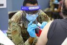 An Air Force medical technician administers the COVID-19 vaccine at a state-run, federally-supported COVID-19 Community Vaccination Center.