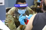 An Air Force medical technician administers the COVID-19 vaccine at a state-run, federally-supported COVID-19 Community Vaccination Center.