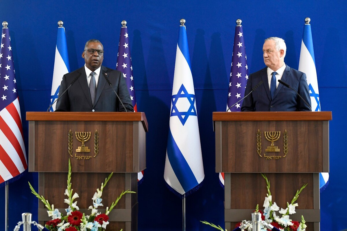 Two men stand on a podium and speak to reporters.
