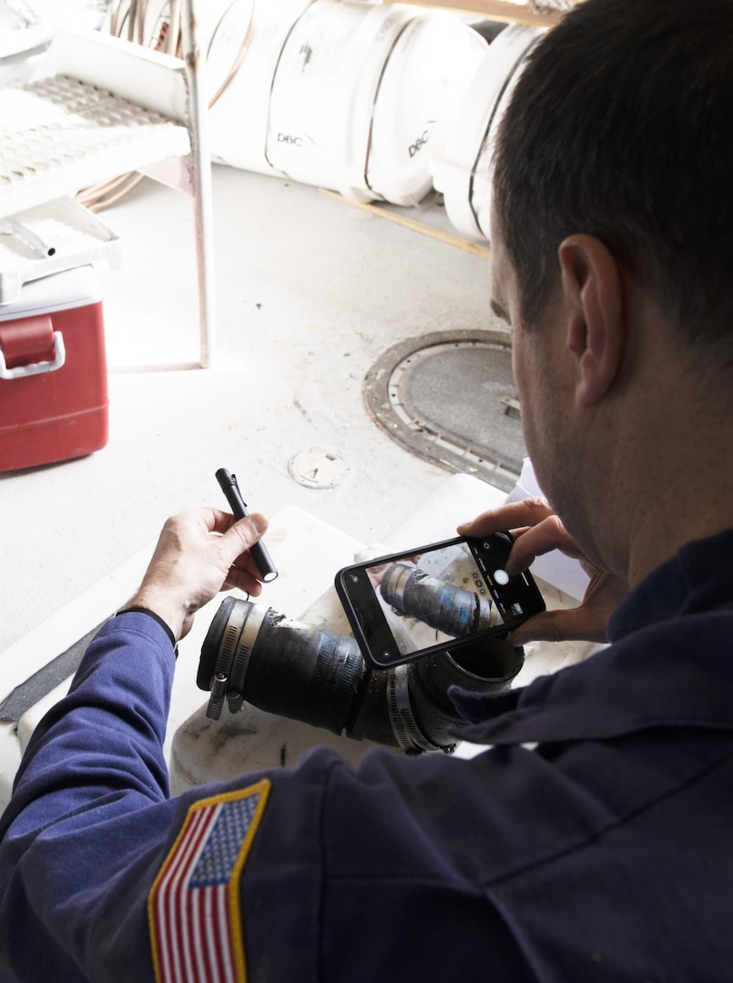 Chief Warrant Officer William Hockensmith, a marine inspector at Coast Guard Marine Safety Unit Portland, documents a damaged pipe during an inspection of the small passenger vessel Adventure Bound at a dry dock in Ilwaco, Washington, March 9, 2020. Small passenger vessels like the Adventure Bound that operate in saltwater routes are required to receive dry dock inspections every two years. (U.S. Coast Guard photo by Petty Officer 1st Class Levi Read)