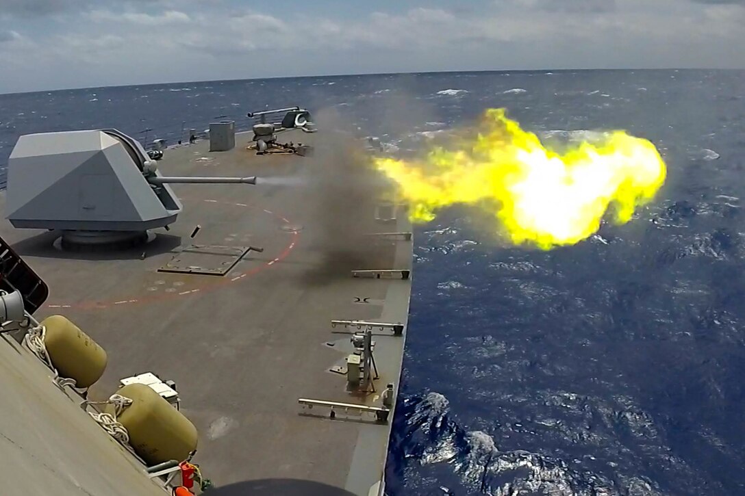 Flame and smoke appear after a large gun is fired on board a ship.