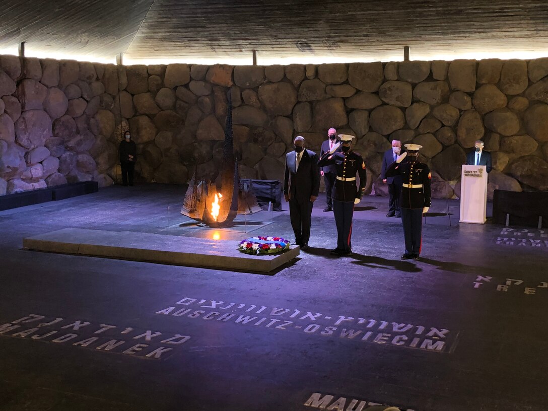 A man stands at attention next to two Marines after laying a wreath at the World Holocaust Remembrance Center.
