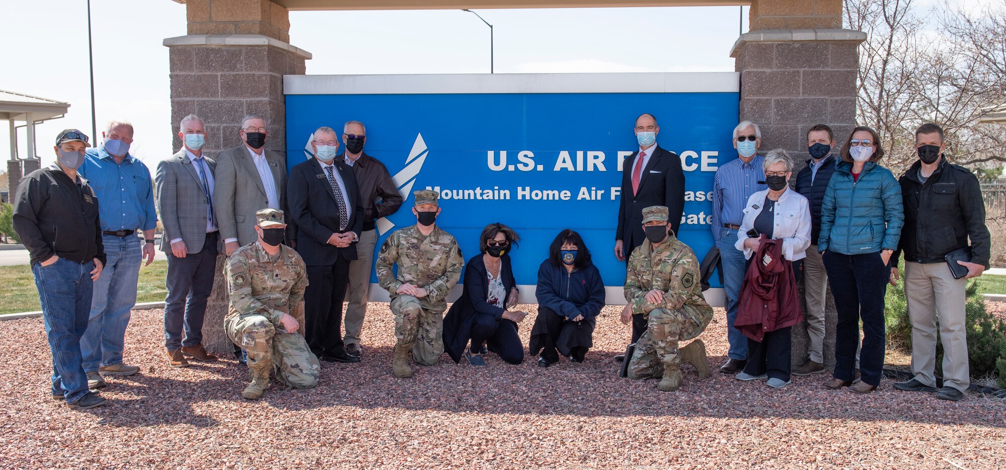A group of Idaho state Representatives pose for a photo with Airmen in front of the Mountain Home Air Force Base greetings sign