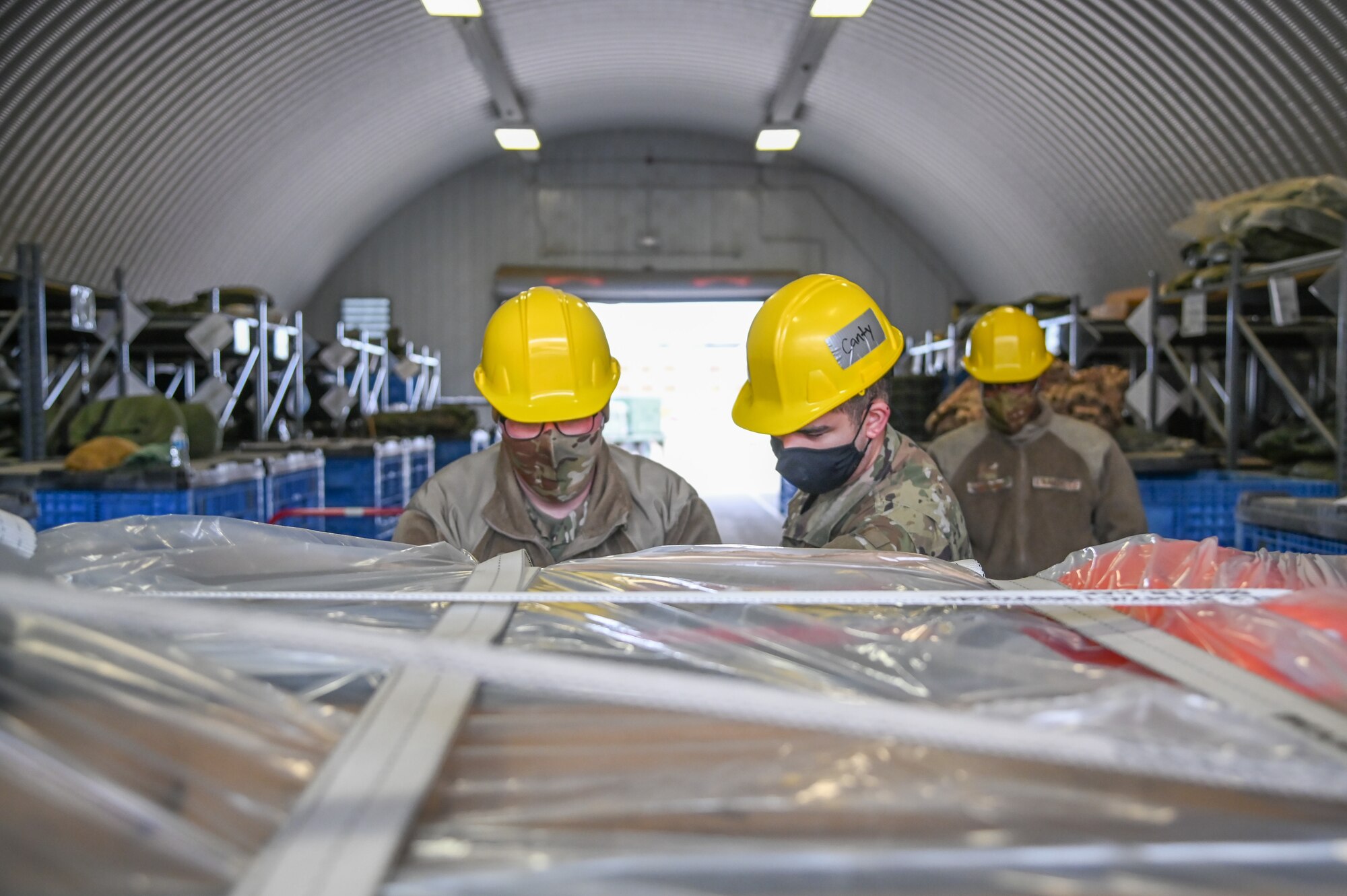Two Airmen tight down straps on cargo cases.