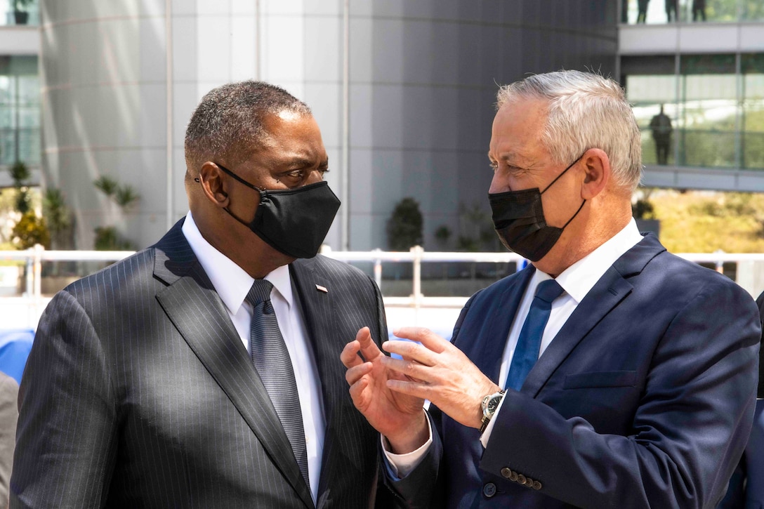 Secretary of Defense Lloyd J. Austin III speaks with Israeli Minister of Defense Benny Gantz, both wearing masks.