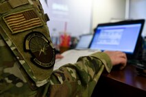 A photo of an airmen's patch while the airmen is sitting in front of a computer