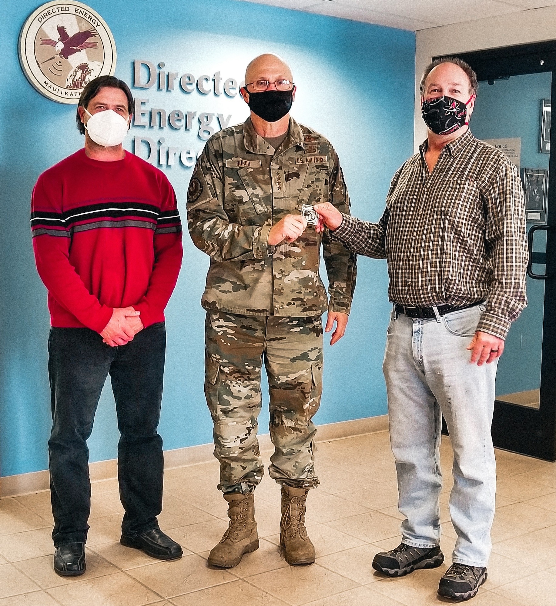 While visiting Kirtland Air Force Base, N.M., Gen. Arnold W. Bunch Jr., commander, Air Force Materiel Command, presented his coveted challenge coin to Pete Finlay (right) and Joe Volza (left) to recognize their team’s contributions in advancing the Air Force’s base defense priorities. (Courtesy photo)