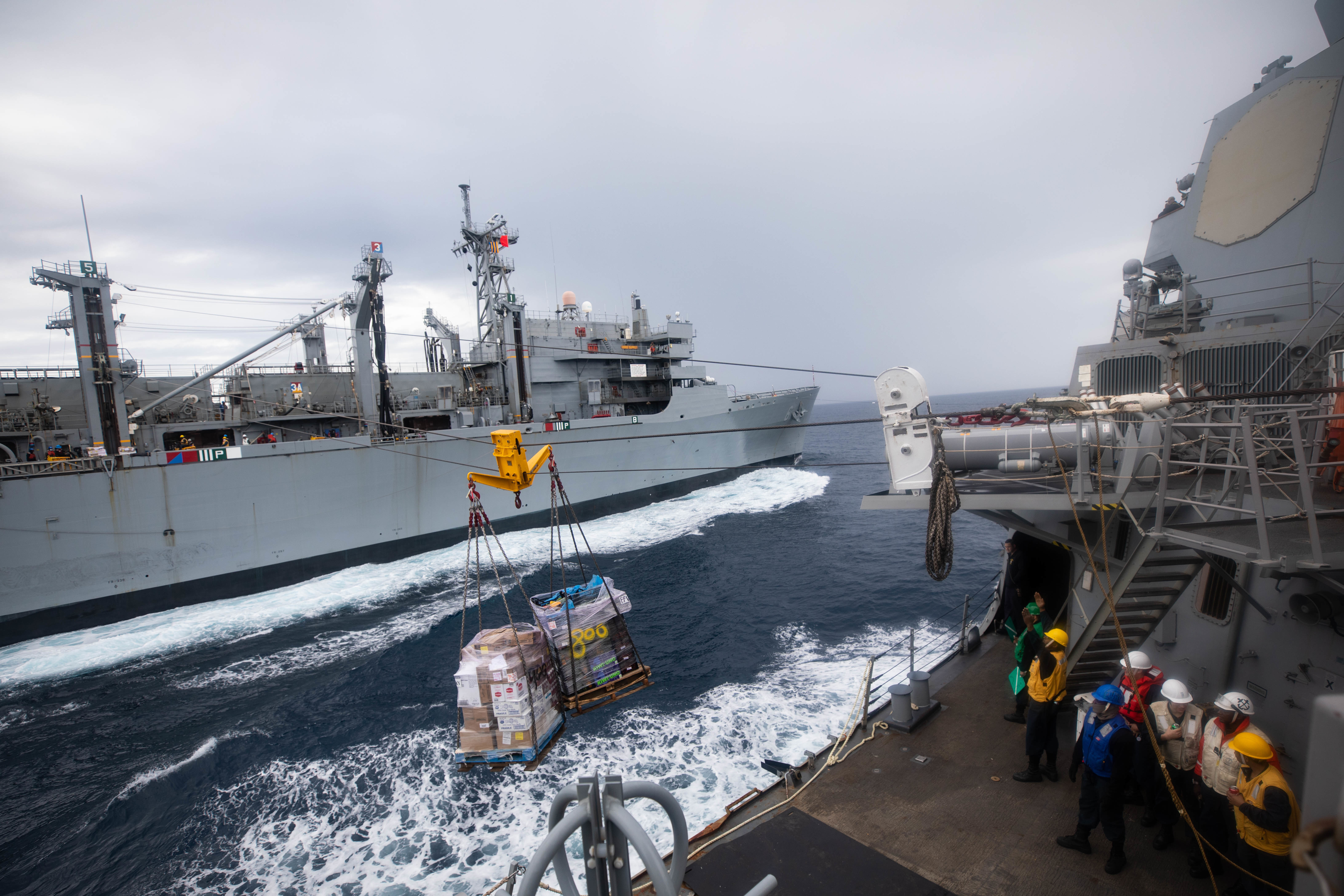 The Arleigh Burke-class guided-missile destroyer USS Roosevelt (DDG 80), right, receives pallets of food stores during a replenishment-at-sea with the fast combat support ship USNS Supply (T-AOE 6), not pictured.