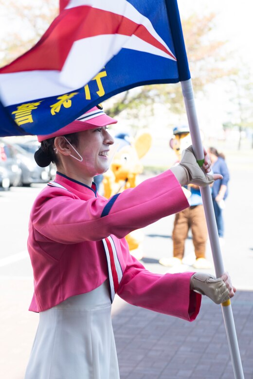 A Japanese National Police Honor Guard member twirls at flag during a concert at the Yokota Community Center on Yokota Air Base, Japan, April 11, 2021. Along with the concert, the JNP also brought out a mascot and handed out information packets in an attempt to educate Yokota members on traffic safety. (U.S. Air Force photo by Staff Sgt. Joshua Edwards)
