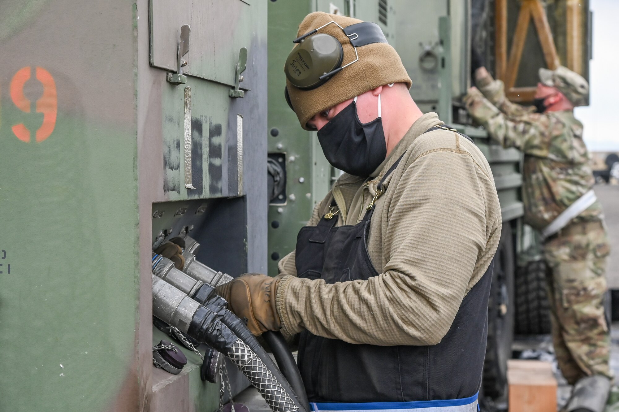 An Airman hooking up an electric cable to a generator.