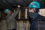 Shop 64 Woodcrafter Robert Penland and Shop 64 Woodcrafter Matthew Thornton use the Hammer Activated Measurement System for Testing and Evaluating Rubber (HAMSTER) on the hull of a submarine.