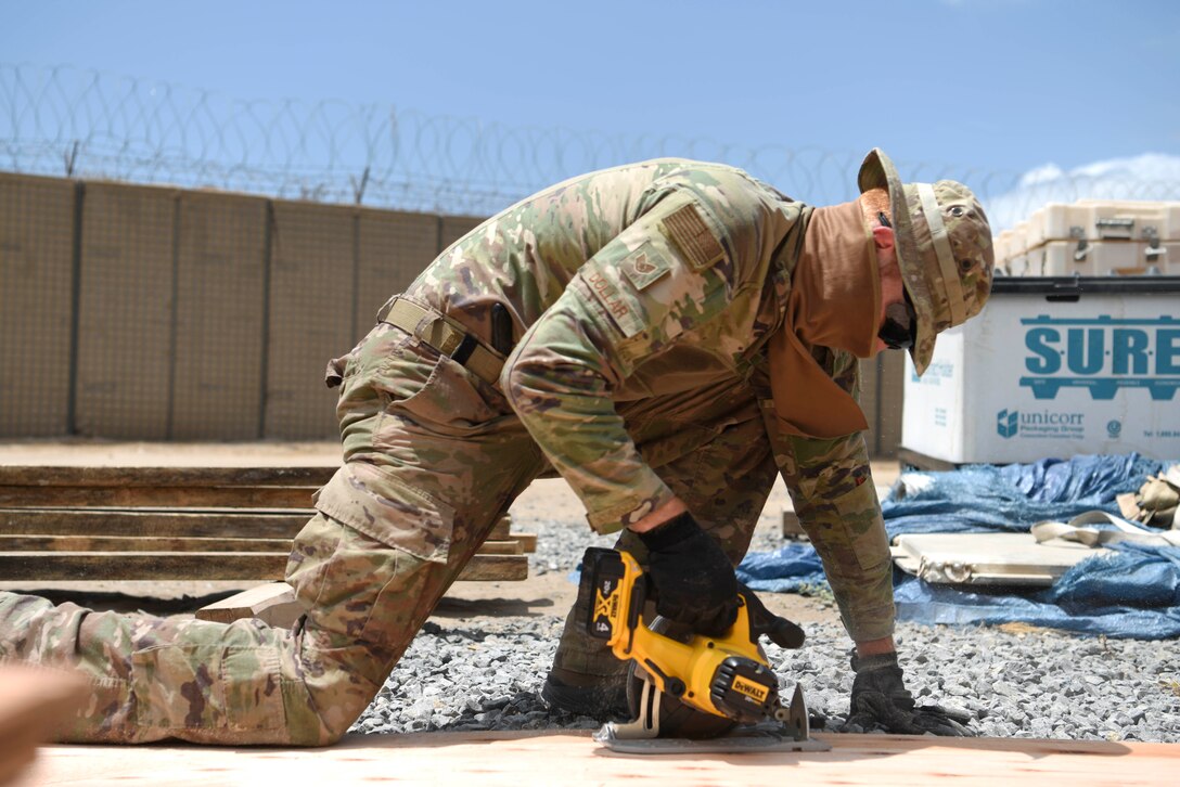 U.S. Air Force Staff Sgt. Garison Dollar, 786th Civil Engineer Squadron structural specialist, cuts a wall template for a tent March 23, 2021, at Camp Simba, Kenya. The 786th CES provided Camp Simba with building new structures, water systems and maintenance so the base can provide continued vigilance to the Combined Joint Task Force-Horn of Africa area of responsibility.