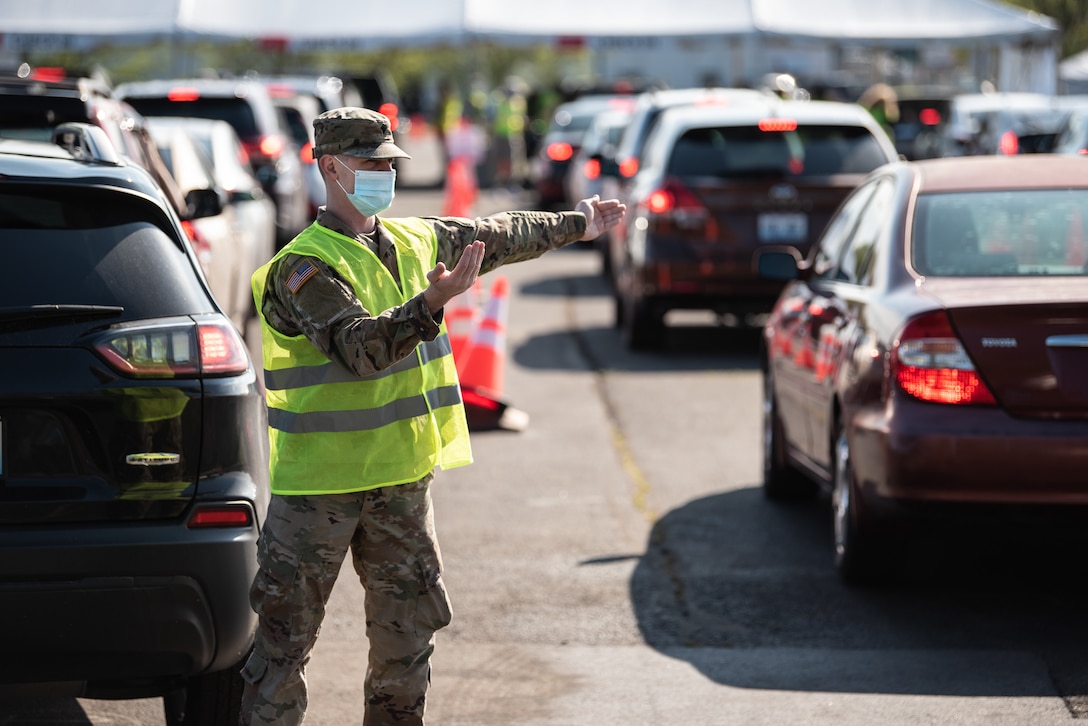 U.S. Army Spc. Logan Kilmon of the Kentucky Army National Guard directs traffic at Kentucky’s largest drive-through COVID-19 vaccination clinic at Cardinal Stadium in Louisville, Ky., April 12, 2021. More than 30 Soldiers and Airmen from the Kentucky Army and Air National Guard are providing direct support to the clinic, which can vaccinate up to 4,000 patients a day. (U.S. Air National Guard photo by Dale Greer)
