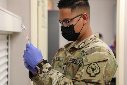 Nevada National Guard Spc. Exequiel Pascual with Joint Task Force 17 measures a dose of the Janssen vaccine at a mobile vaccination unit site in Pahrump, Nevada, April 8, 2021. The Guard and partners and helping facilitate access to the COVID-19 vaccine in rural Nevada.