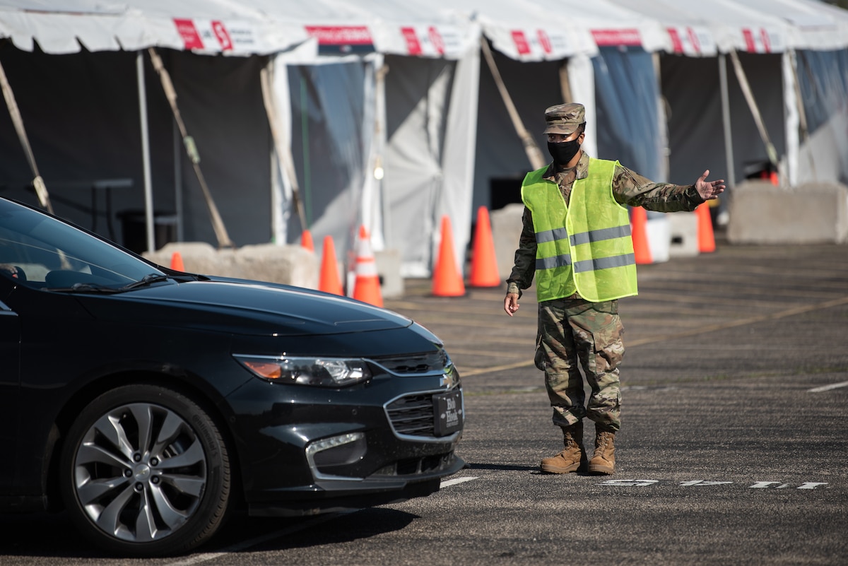 U.S. Air Force Senior Airman Morgan Thomas of the Kentucky Air National Guard directs traffic at Kentucky’s largest drive-through COVID-19 vaccination clinic at Cardinal Stadium in Louisville, Ky., April 12, 2021. More than 30 Soldiers and Airmen from the Kentucky Army and Air National Guard are providing direct support to the clinic, which can vaccinate up to 4,000 patients a day. (U.S. Air National Guard photo by Dale Greer)