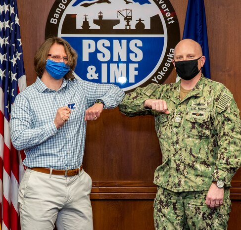 Capt. Jip Mosman, commander, Puget Sound Naval Shipyard & Intermediate Maintenance Facility, presents Mike Tracy, process management branch manager, Code 220, Resources, Training & Processes, with a Bravo Zulu sticker April 13, 2021, for co-leading a team with Bryson Delima, 2380.1RW Radioactive Waste branch head, that codified a sustainable engineering execution system, which was shared with all four U.S. Navy shipyards. Their combined efforts improved the turnaround time for Deficiency Log resolution from 2.4 days to less than one day by addressing visibility and behaviors at all levels of the command.