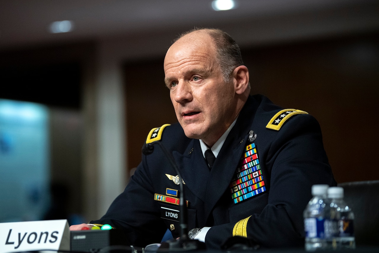 A man dressed in a military uniform speaks into a microphone.