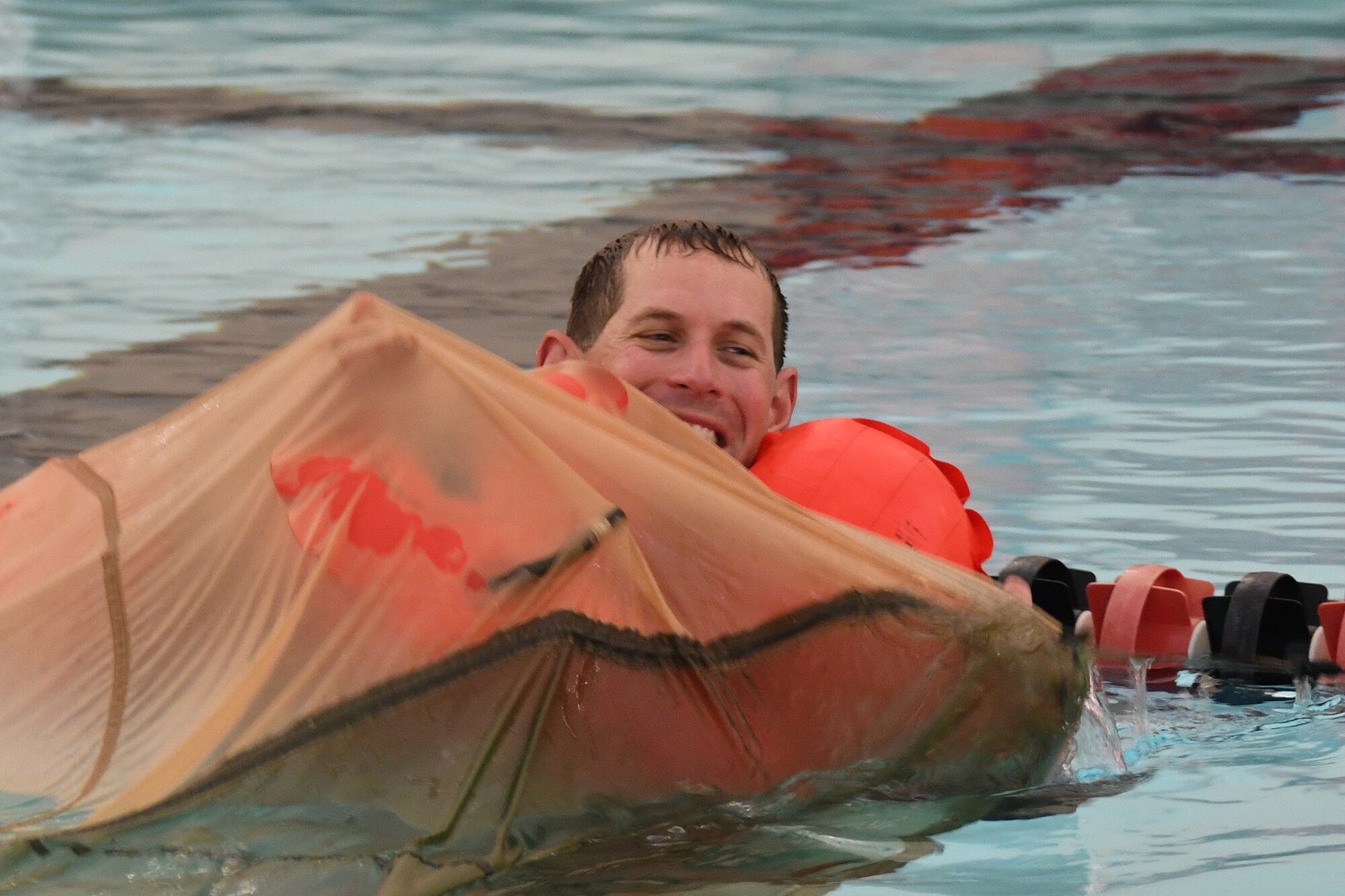 Lt. Col. Steve Stroney, 910th Operations Group evaluator pilot, emerges from underneath a parachute canopy floating in the water during an aircrew water survival refresher training event at Youngstown State University’s Beeghly Natatorium Olympic Swimming Pool, April 11, 2021.