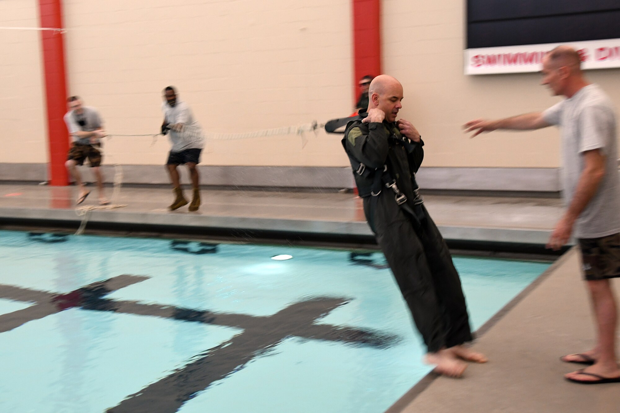 Air Force Reserve Lt. Col. Frank Galati, 757th Airlift Squadron Director of Operations based at nearby Youngstown Air Reserve Station, is yanked backwards from the swimming pool deck as part of a water landing parachute harness drag and release exercise during an aircrew water survival refresher training event at Youngstown State University’s Beeghly Natatorium Olympic Swimming Pool, April 11, 2021. Galati was among a group of 34 Reserve Citizen Airmen assigned to the squadrons of the 910th Operations Group, participating in the training event, which is a tri-annual requirement for all aircrew members. The training was broken into several blocks including aircrew familiarization of AFE water survival accessories aboard the 910th’s C-130H Hercules tactical cargo aircraft; 20-person and single-person life raft operations; swimming techniques; a water landing parachute harness drag and release as well as water landing parachute disentangling techniques.