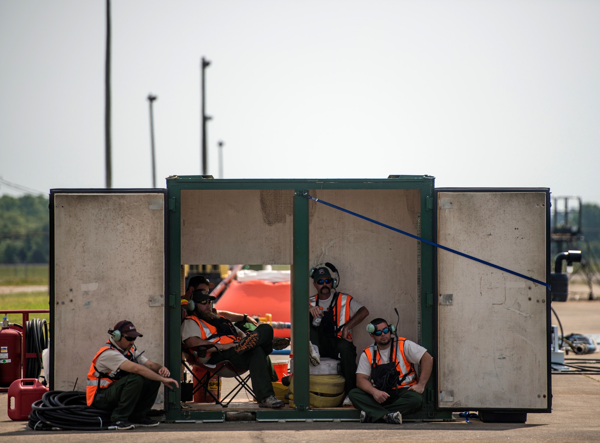 North Carolina Forest Service members stay away from the sun as they wait in the shadows of a storage box while all the MAFFS C-130's have taken off during their training missions. (U.S. Air Force photo/Staff Sgt. Andrew Lee)