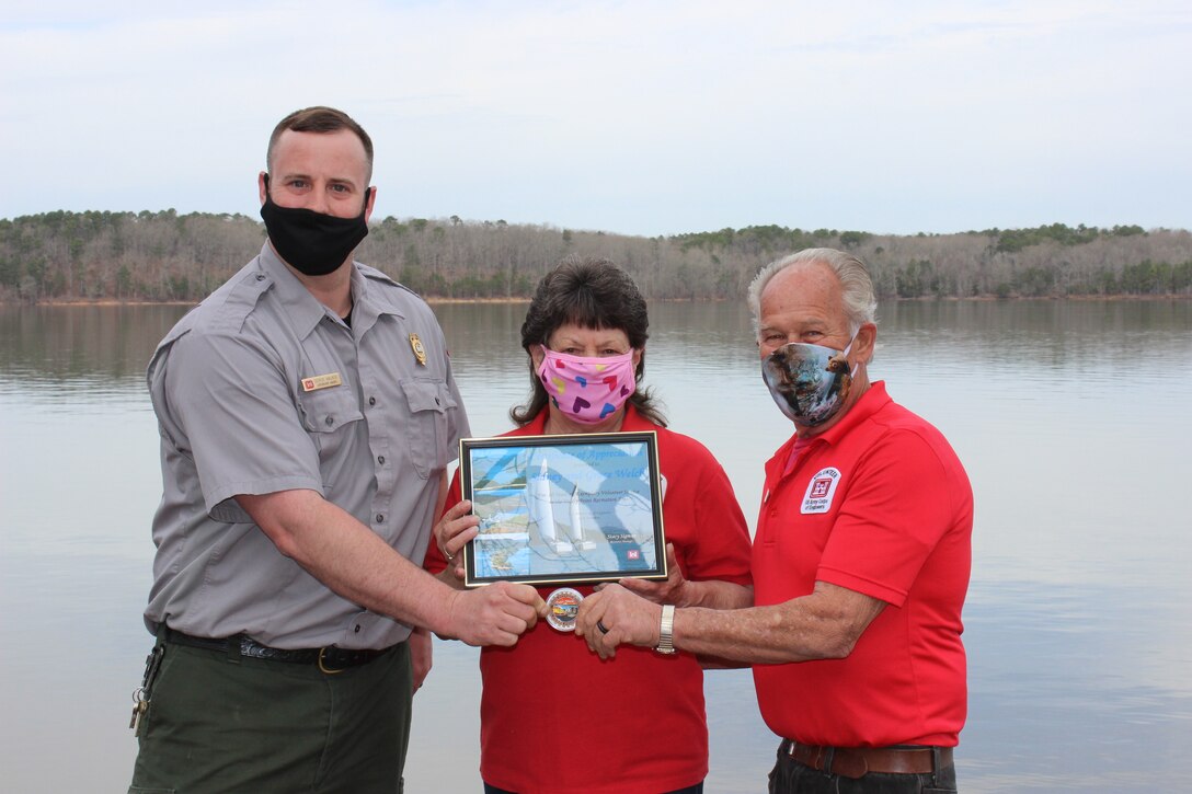 Lake Ouachita Supervisory Natural Resources Specialist Derick Walker (left) presents the Volunteer Excellence Coin to Grace and Sidney Welch. The Welches received the honor from the U.S. Army Corps of Engineers Vicksburg District and the Corps Foundation for their ten years of dedicated volunteer service to the lake’s Denby Point Recreation Area.