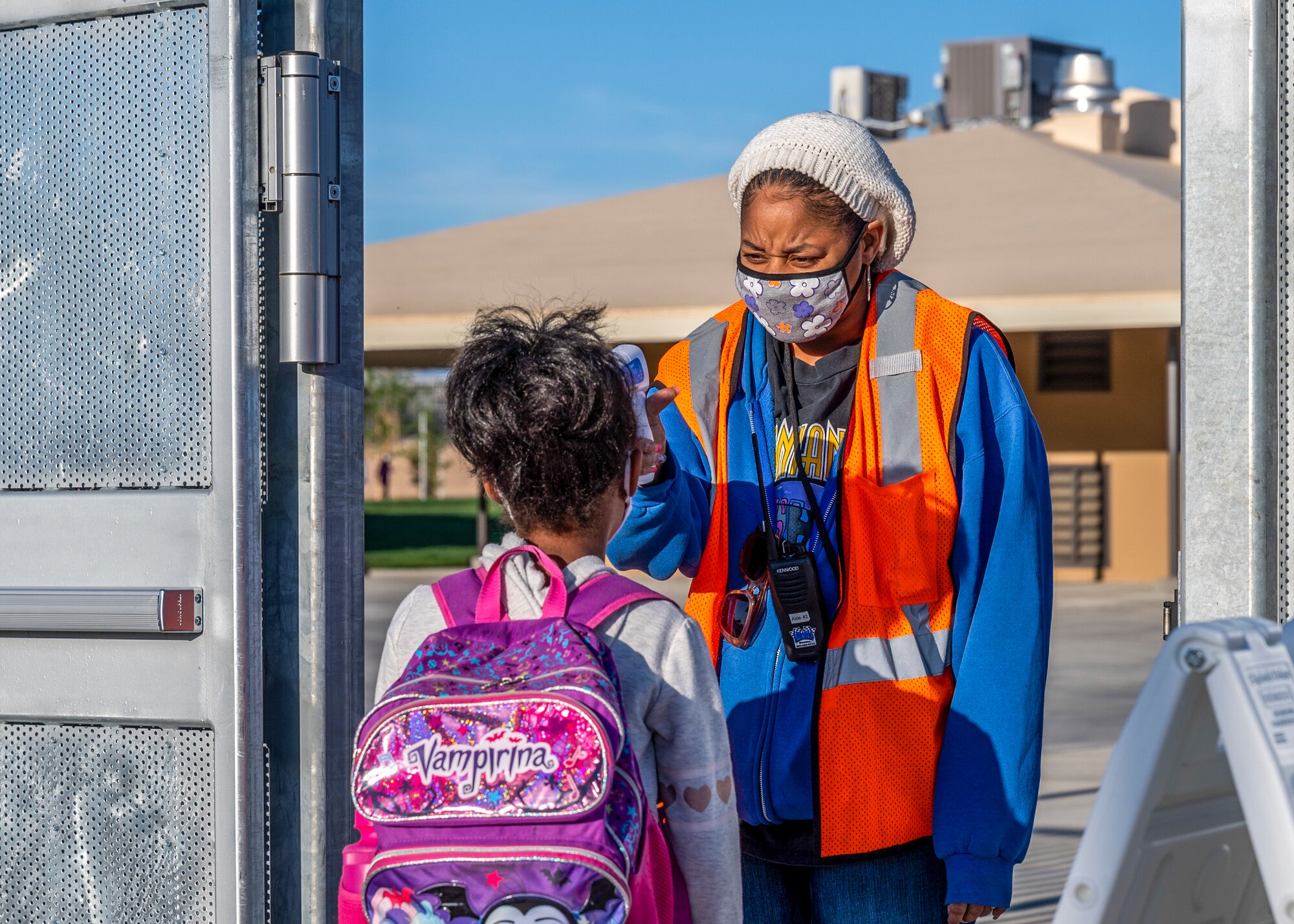 A Bailey Elementary School faculty member checks a student's temperature before entering school premises during the first day of physical in-person learning and grand reopening of Bailey Elementary School on Edwards Air Force Base, California, April 12. (Air Force photo by Giancarlo Casem)