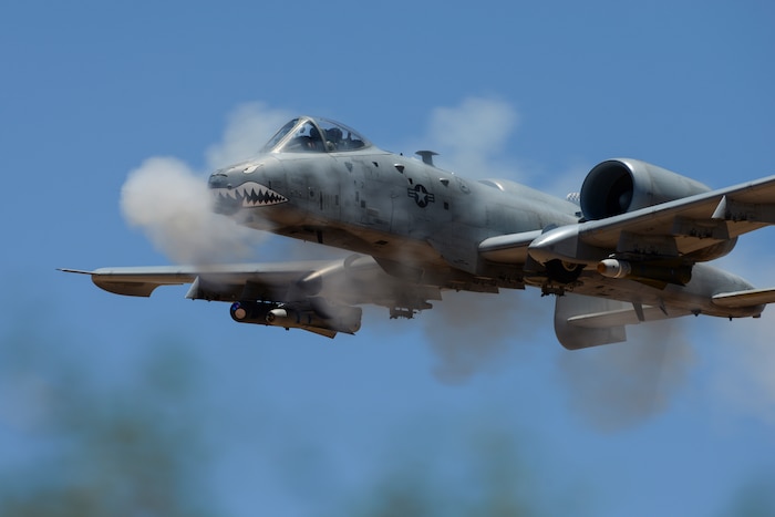 A photo of a flying aircraft with smoke around it.