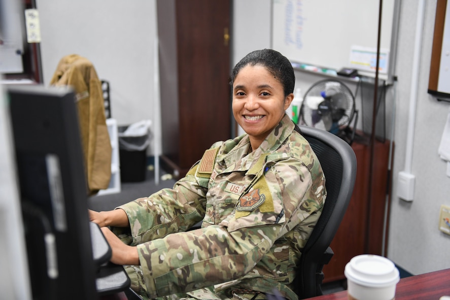 Airman poses for photo at desk.