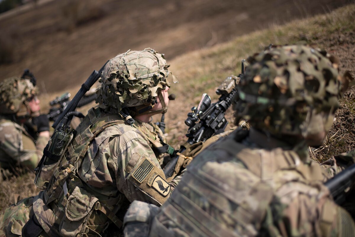 Three soldiers with guns lie on their stomachs and take aim.