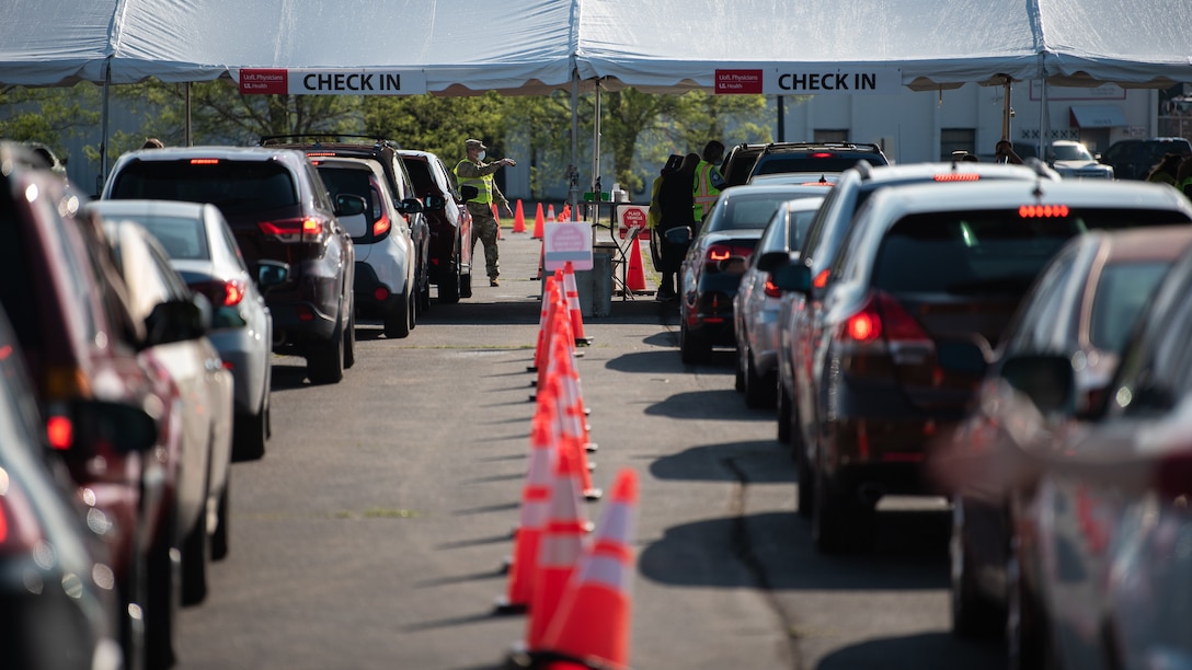 U.S. Army Sgt. Nicholas Wentworth of the Kentucky Army National Guard directs traffic at Kentucky’s largest drive-through COVID-19 vaccination clinic at Cardinal Stadium in Louisville, Ky., April 12, 2021. More than 30 Soldiers and Airmen from the Kentucky Army and Air National Guard are providing direct support to the clinic, which can vaccinate up to 4,000 patients a day. (U.S. Air National Guard photo by Dale Greer)