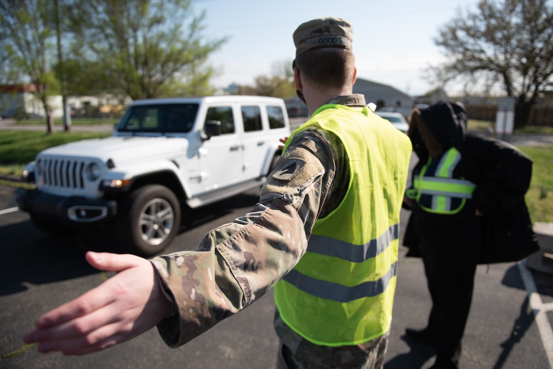 U.S. Army Pvt. Kevin Good of the Kentucky Army National Guard directs traffic at Kentucky’s largest drive-through COVID-19 vaccination clinic at Cardinal Stadium in Louisville, Ky., April 12, 2021. More than 30 Soldiers and Airmen from the Kentucky Army and Air National Guard are providing direct support to the clinic, which can vaccinate up to 4,000 patients a day. (U.S. Air National Guard photo by Dale Greer)