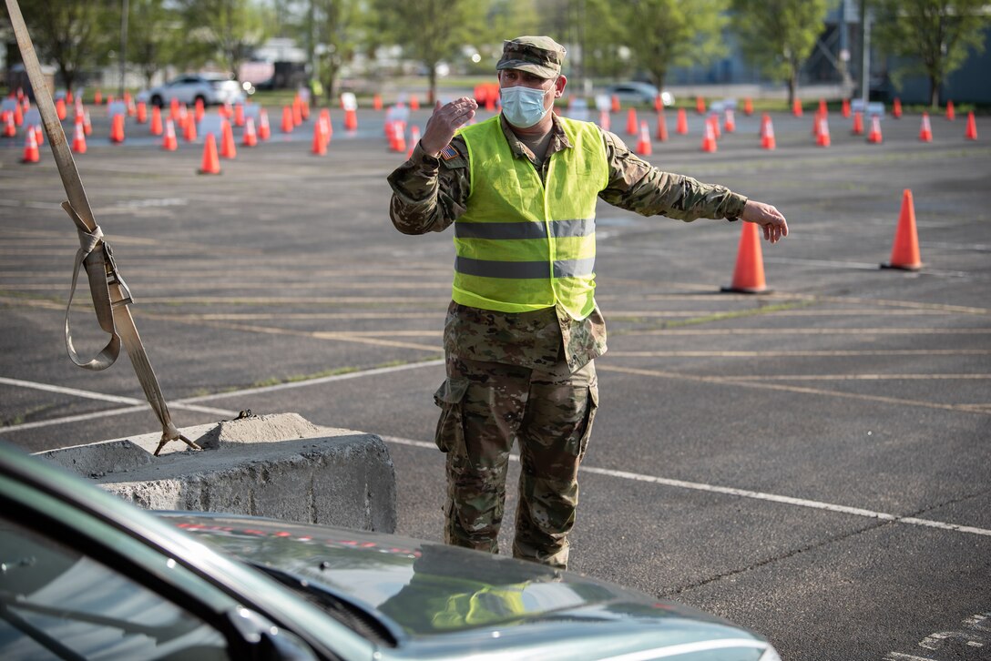 U.S. Army Sgt. Nicholas Wentworth of the Kentucky Army National Guard directs traffic at Kentucky’s largest drive-through COVID-19 vaccination clinic at Cardinal Stadium in Louisville, Ky., April 12, 2021. More than 30 Soldiers and Airmen from the Kentucky Army and Air National Guard are providing direct support to the clinic, which can vaccinate up to 4,000 patients a day. (U.S. Air National Guard photo by Dale Greer)