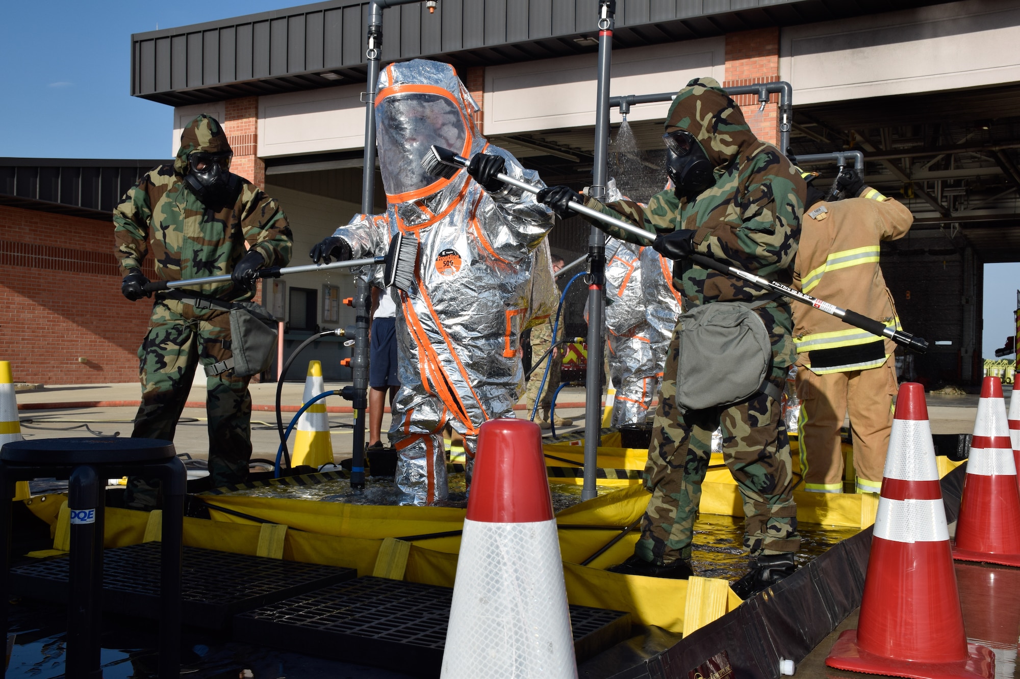 The 433rd Civil Engineer Squadron and Joint Base San Antonio Fire Department firefighters brush and wash the contaminates off of firefighters in hazardous material suits during a joint training exercise at Joint Base San Antonio-Lackland, Texas, April 8, 2021. The 433rd CES and JBSA Fire Department firefighters wore mission oriented protective posture gear and HAZMAT suits to protect themselves against simulated contaminates from patients and personnel. (U.S. Air Force photo by Senior Airman Brittany Wich)