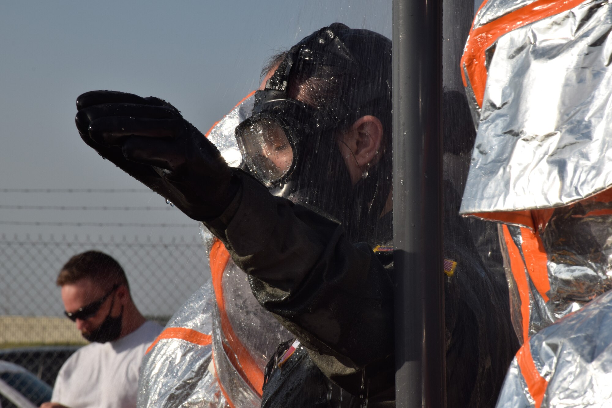 Senior Airman Cassandra Csanyi, 433rd Aeromedical Evacuation Squadron flight medical technician, walks through a decontamination station during a joint training exercise at Joint Base San Antonio-Lackland, Texas, April 8, 2021. The 433rd Civil Engineer Squadron and Joint Base San Antonio Fire Department firefighters assembled a decontamination process of brushing and washing contaminates away from patients and personnel. (U.S. Air Force photo by Senior Airman Brittany Wich)