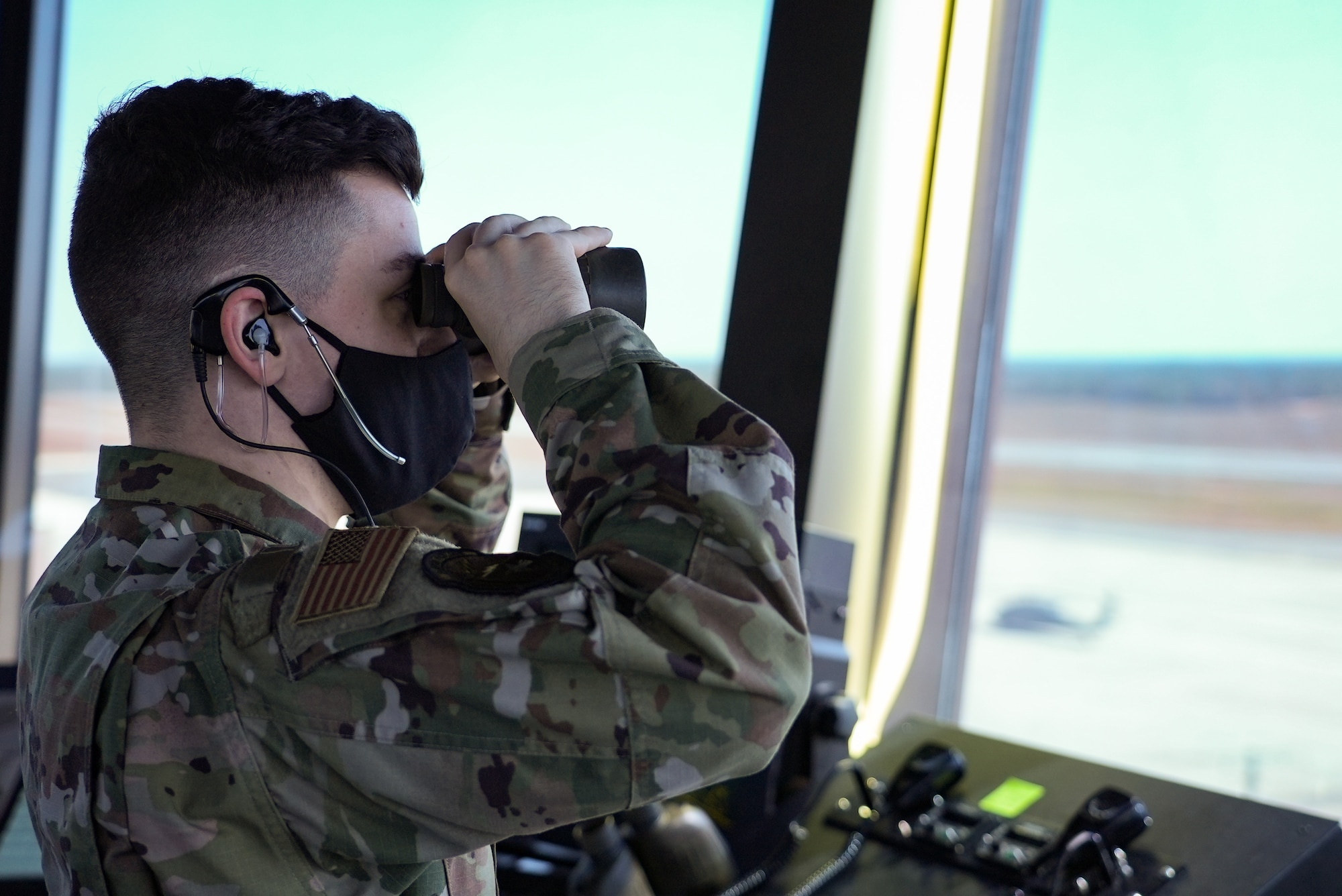 Young Airman looks through binoculars out of the tower window.