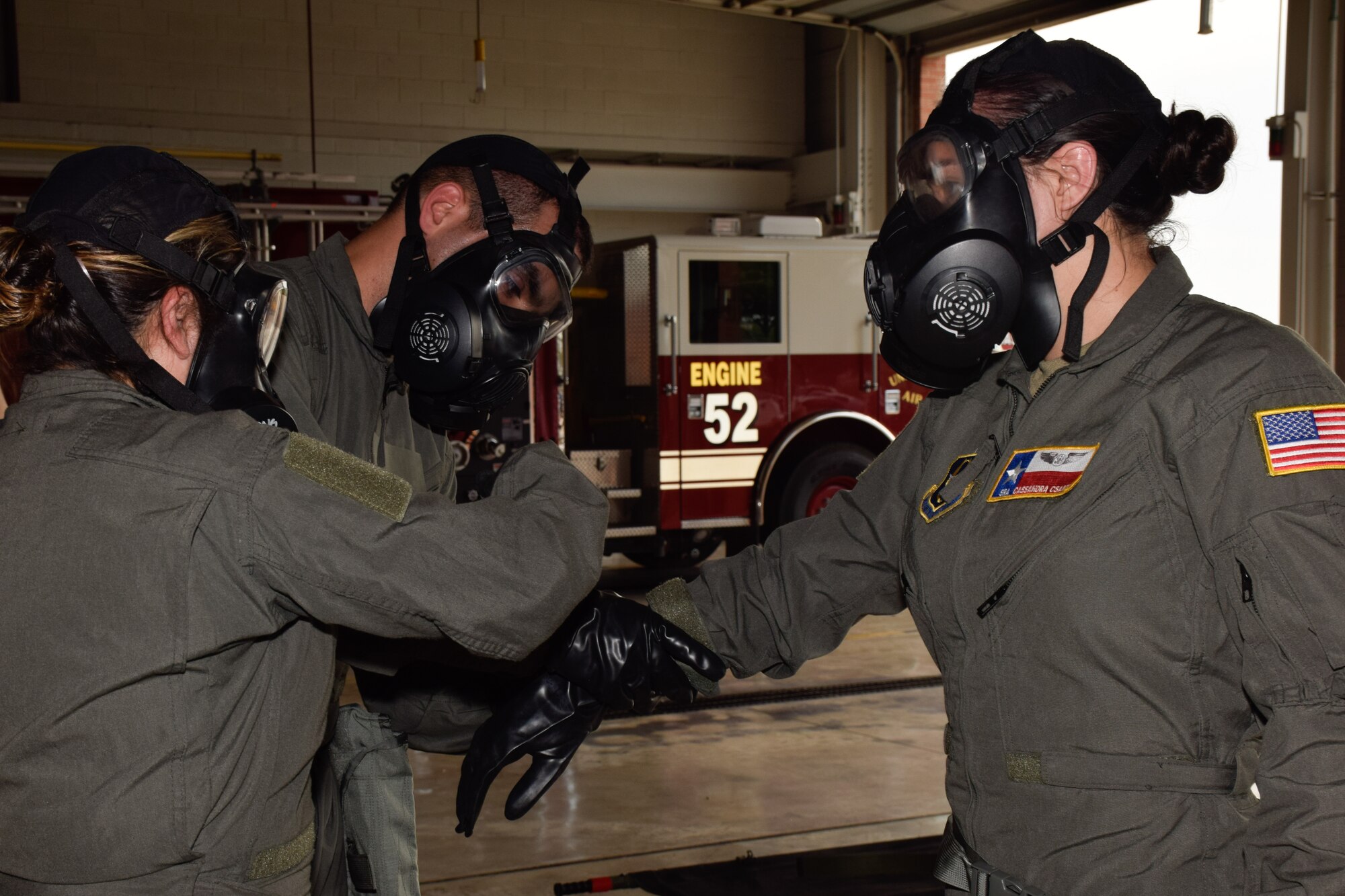 Tech Sgt. Alison Espinoza, 433rd Aeromedical Evacuation Squadron flight medical technician, and Capt. Damian Gonzalez, 911th AES flight nurse, assist Senior Airman Cassandra Csanyi, 433rd AES flight medical technician, in putting on her gloves during a joint training exercise at Joint Base San Antonio-Lackland, Texas, April 8, 2021. The flight crew wore mission oriented protective posture gear to simulate providing care to chemical agent-contaminated patients. (U.S. Air Force photo by Senior Airman Brittany Wich)