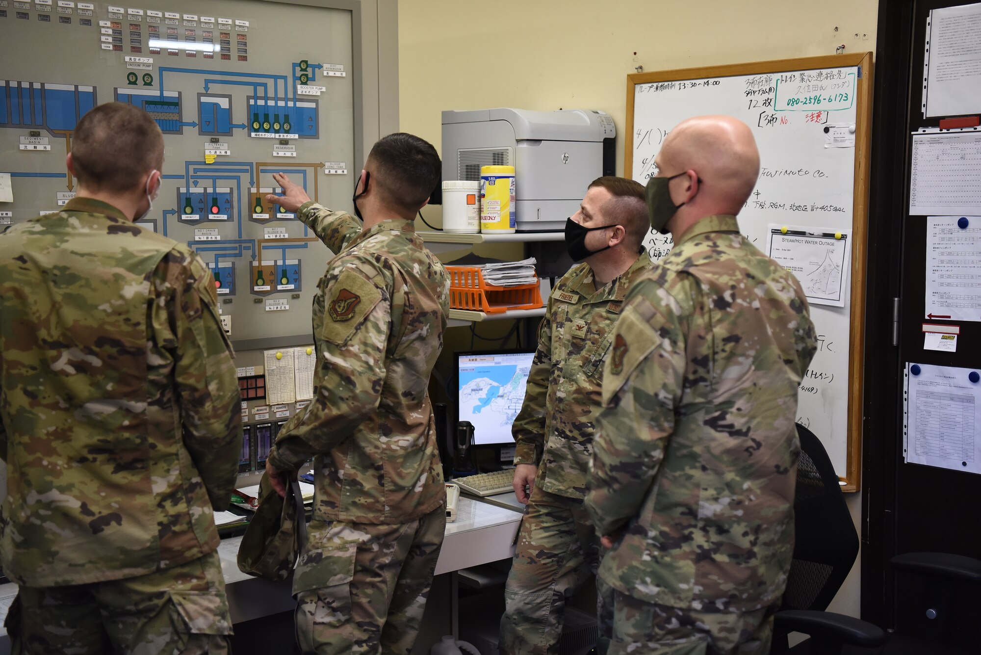 Group of military members look at a control station.
