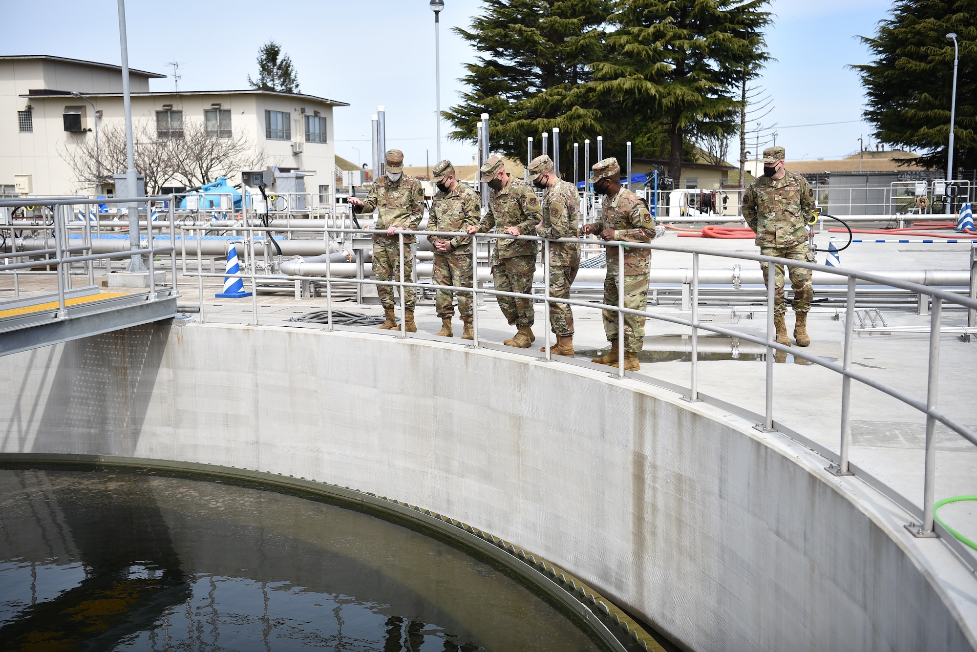 Group of military members look into a clarifying tank.