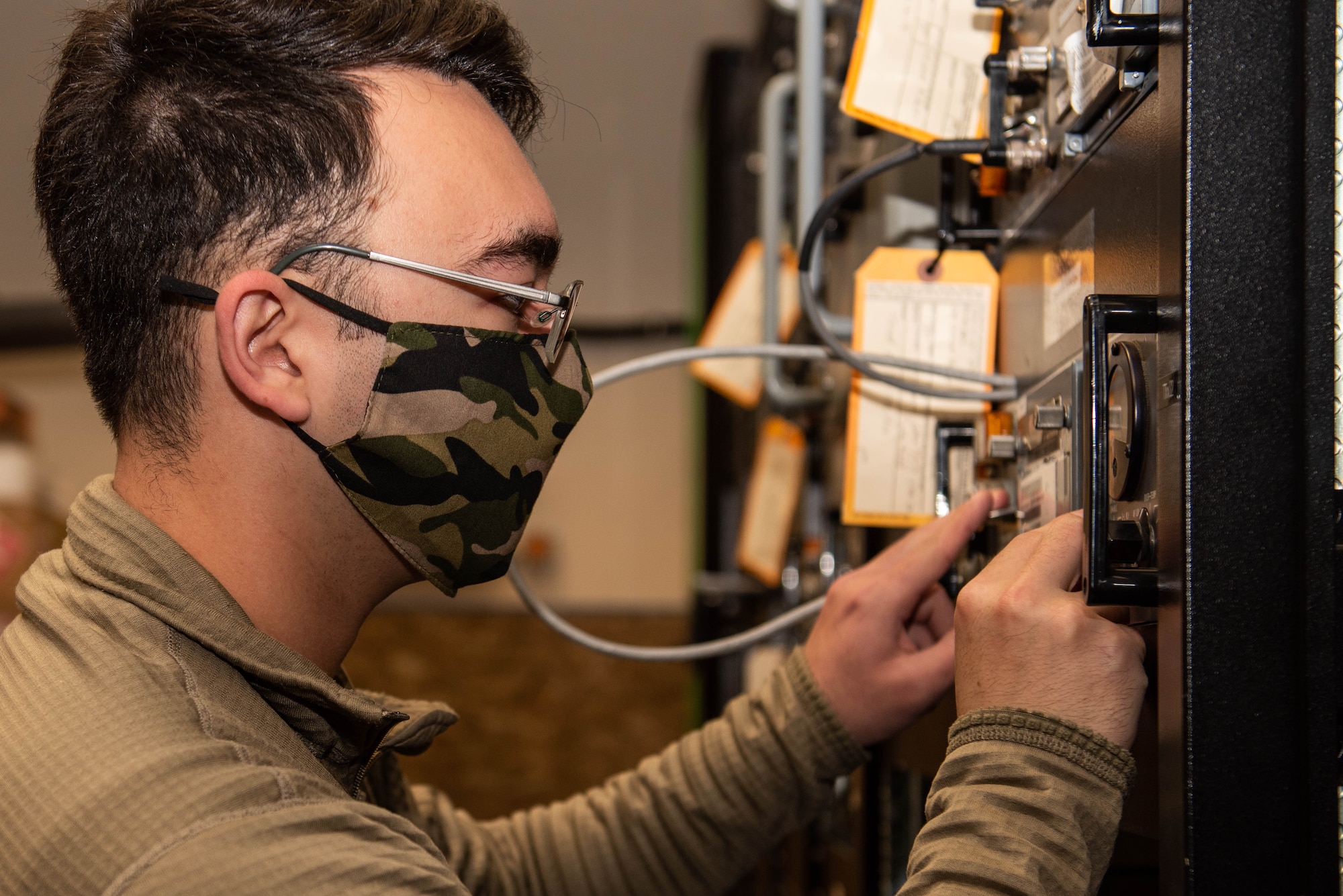A RAWS Airman works to fix an wall-mounted radio transmitter