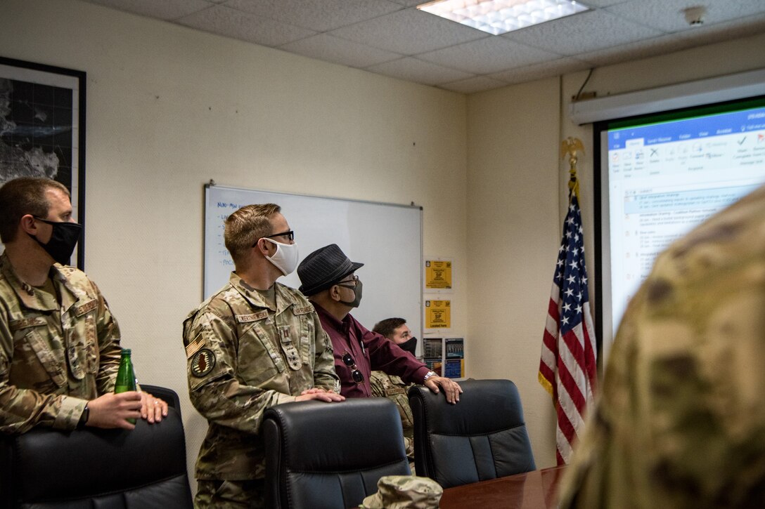 men stand in a meeting around a conference table