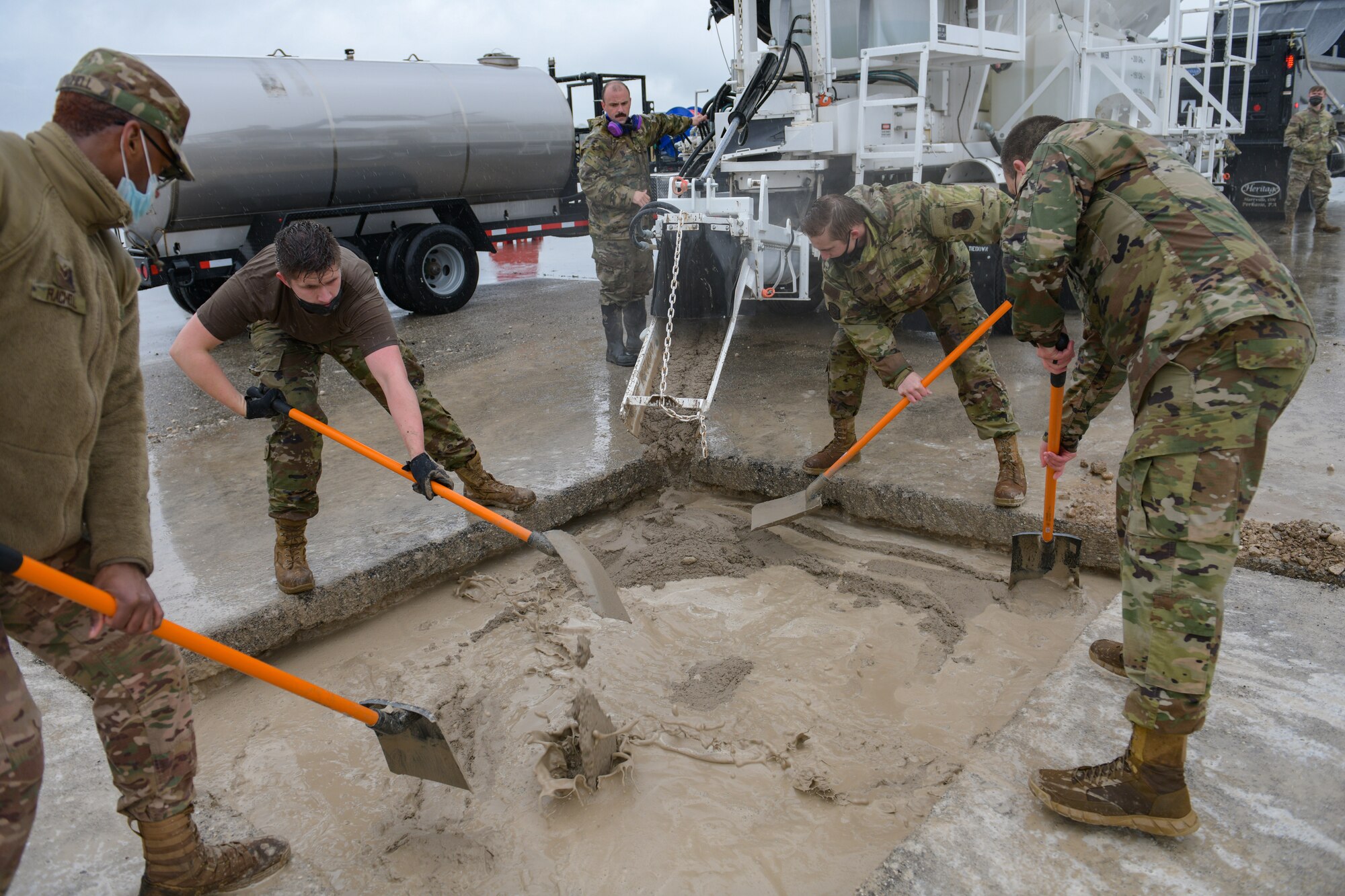 Airmen assigned to the 31st Civil Engineer Squadron spread concrete mixture into a crater during a base defense readiness exercise at Aviano Air Base, Italy, April 12, 2021. During Rapid Airfield Damage Repair (RADR) operations on the flightline, Airmen repaired 18 small craters in approximately eight hours. (U.S. Air Force photo by Airman 1st Class Brooke Moeder)