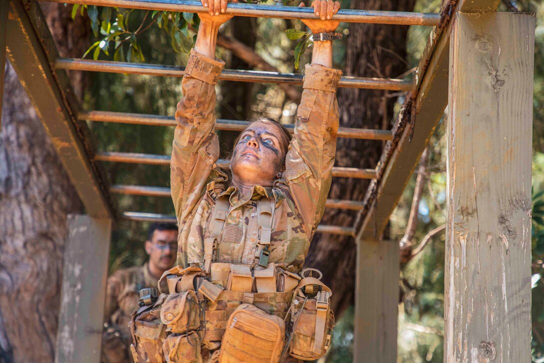 A soldier scales monkey bars.
