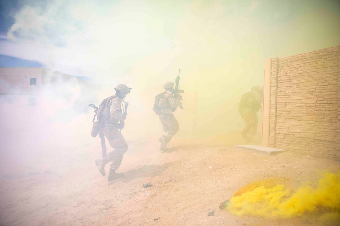Marines move through an area as smoke surrounds them.