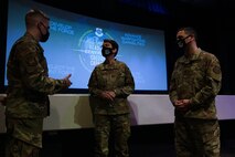 Three people speak in front of a stage