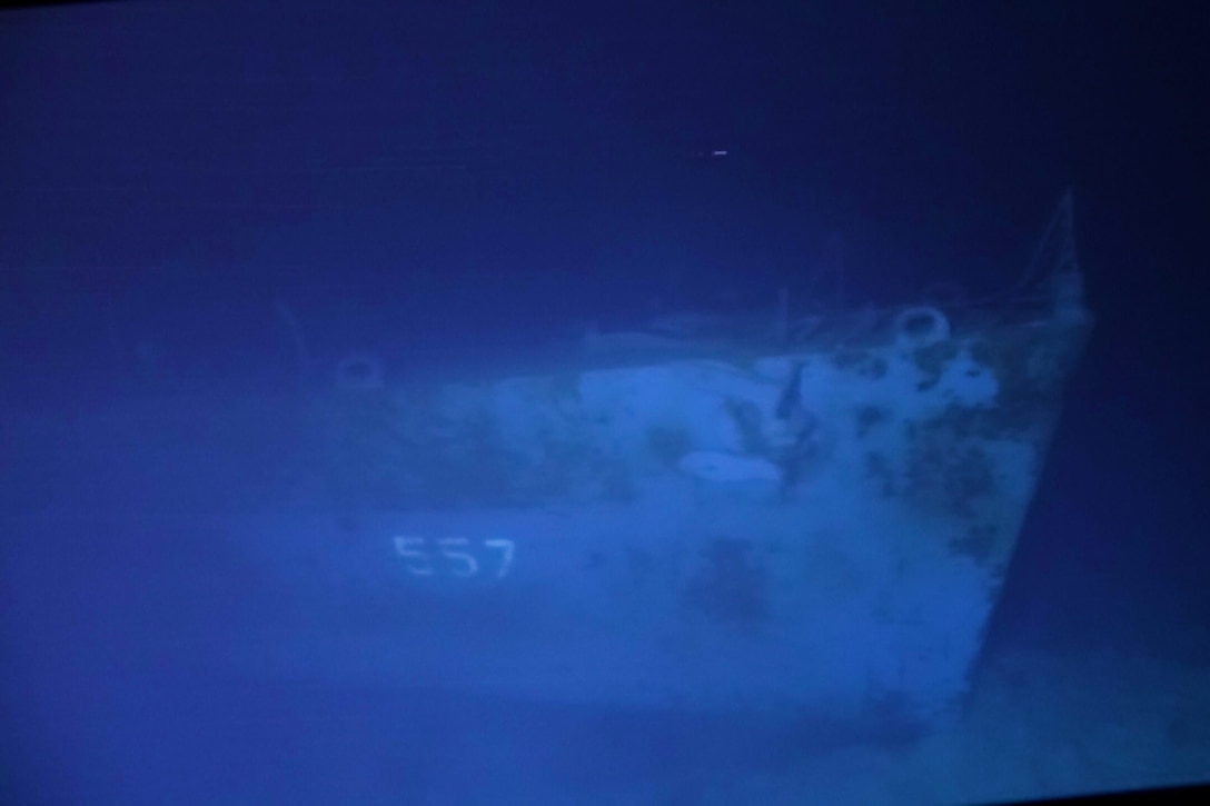 Underwater wreckage of a ship shows the number "557."