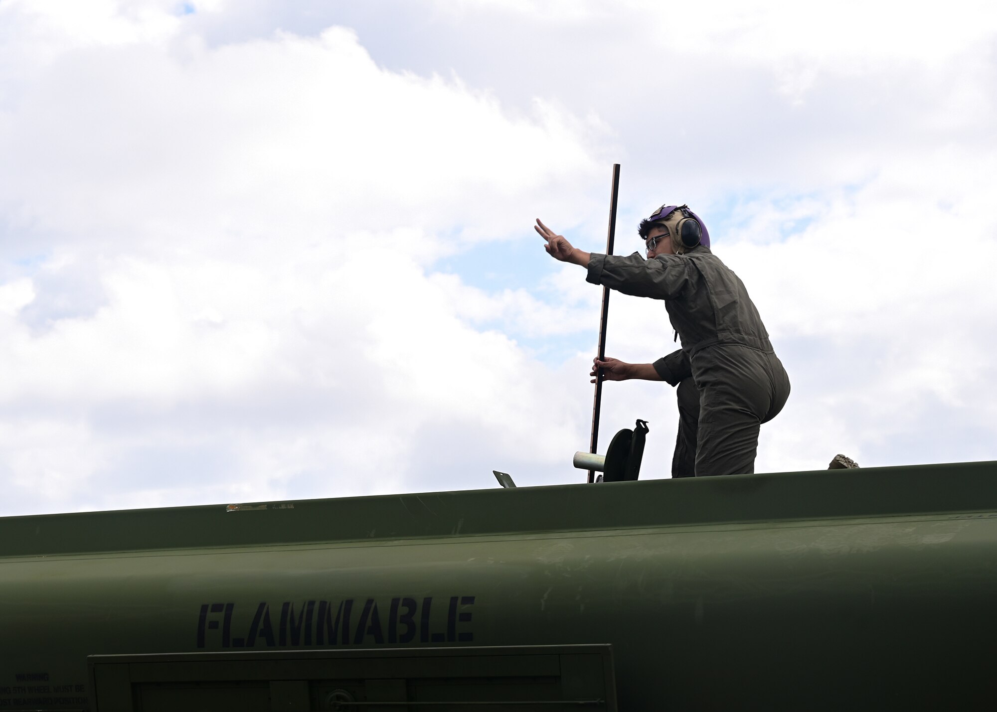 A Marine kneels on top of an aircraft refueling tanker